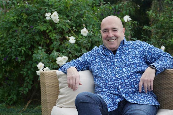 international telenovela author Enrique Torres sitting outside his home backyard, wearing a blue shirt